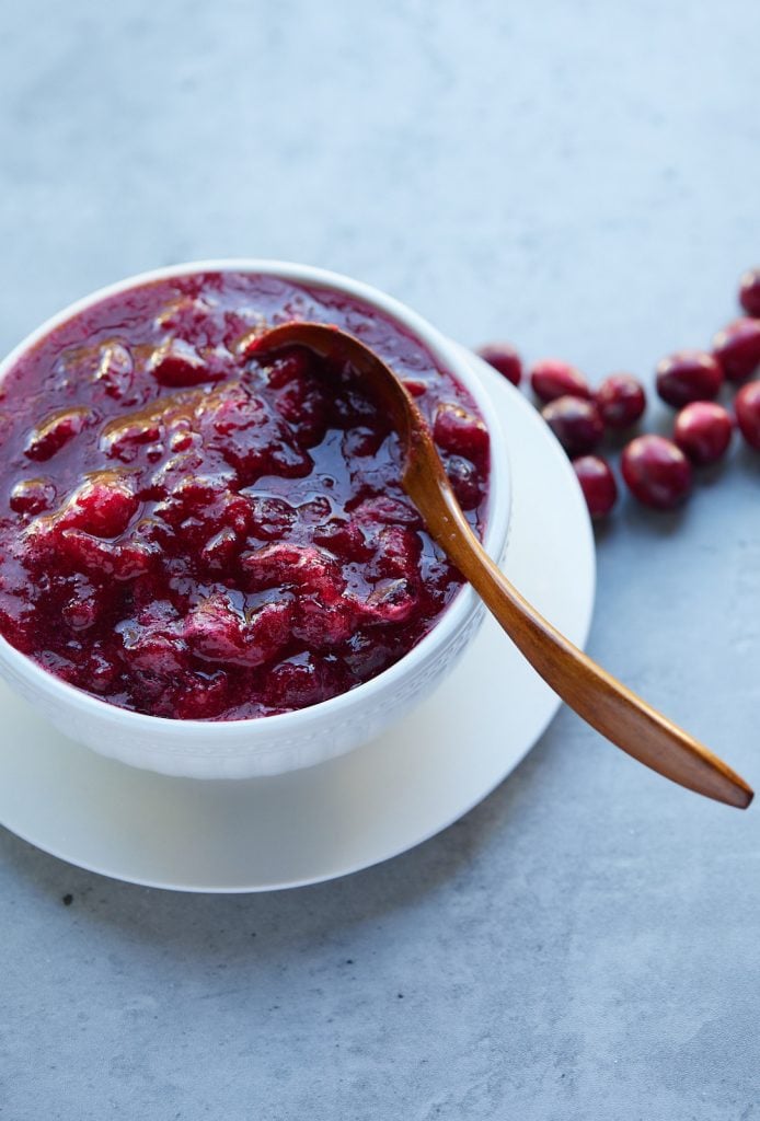 Cranberry sauce served in a white bowl with a gold spoon.