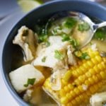 Fish soup with corn served in a bowl with a spoon.