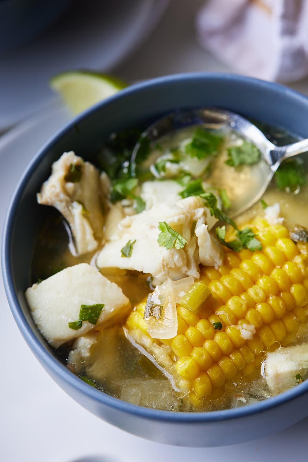 Fish soup with corn served in a bowl with a spoon.