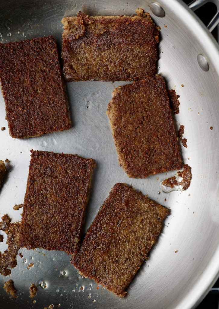 Cooked livermush slices in a skillet.