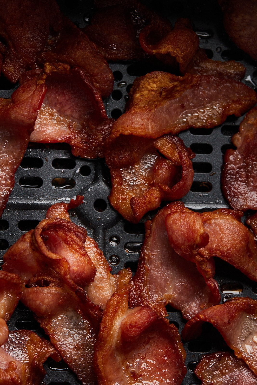 5 pieces of cooked bacon in the air fryer basket.