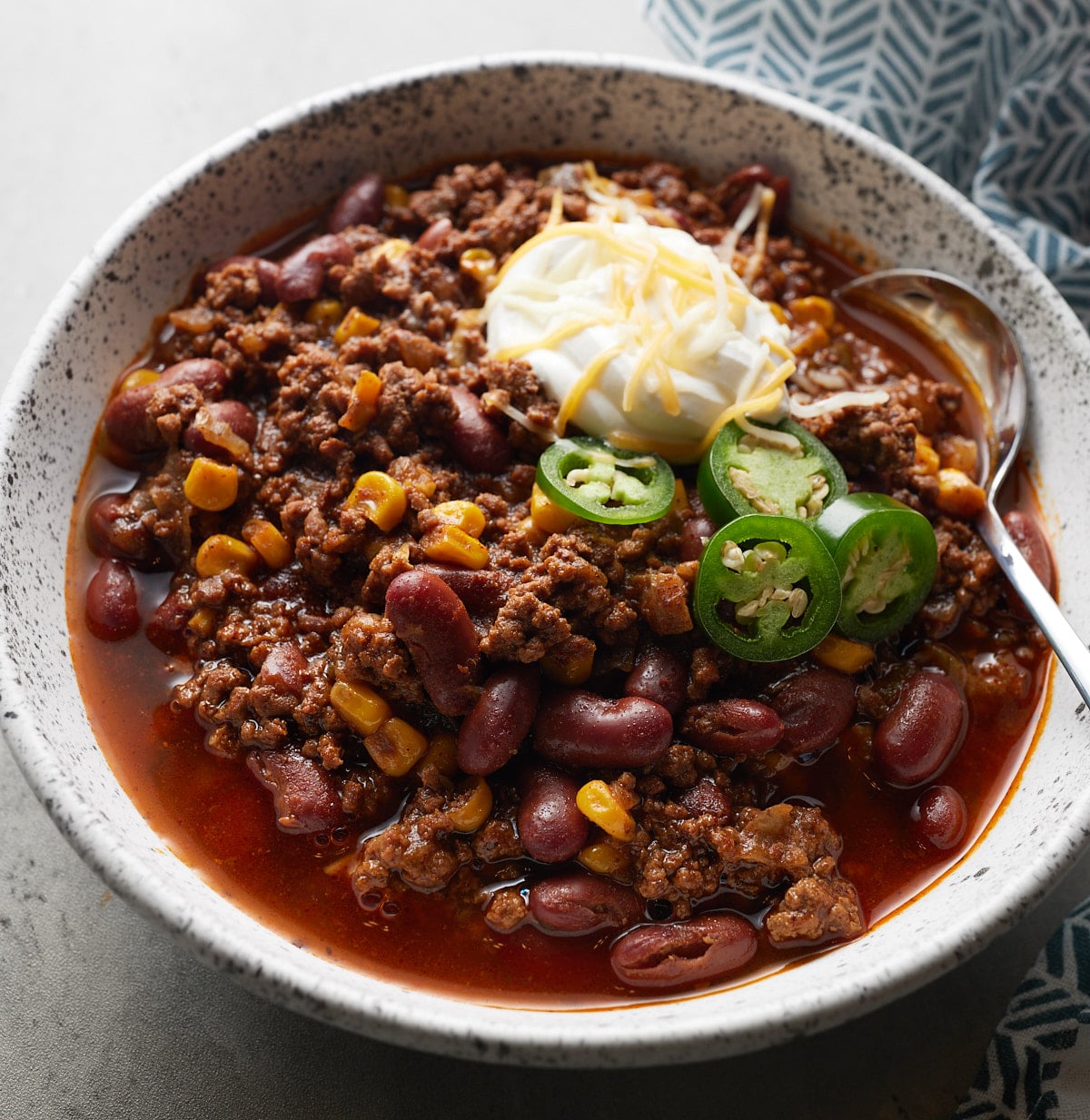 Chili served in a white bowl with a spoon.