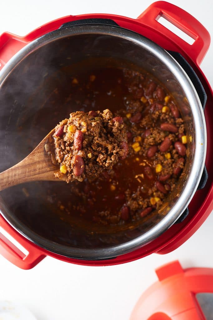 Some of the cooked shili on a wooden spoon over the Instant Pot.