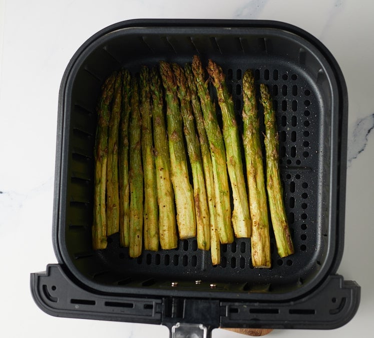 The cooked asparagus in the air fryer basket.