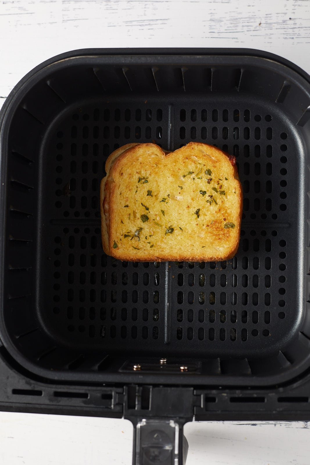 The grilled cheese in an air fryer basket.