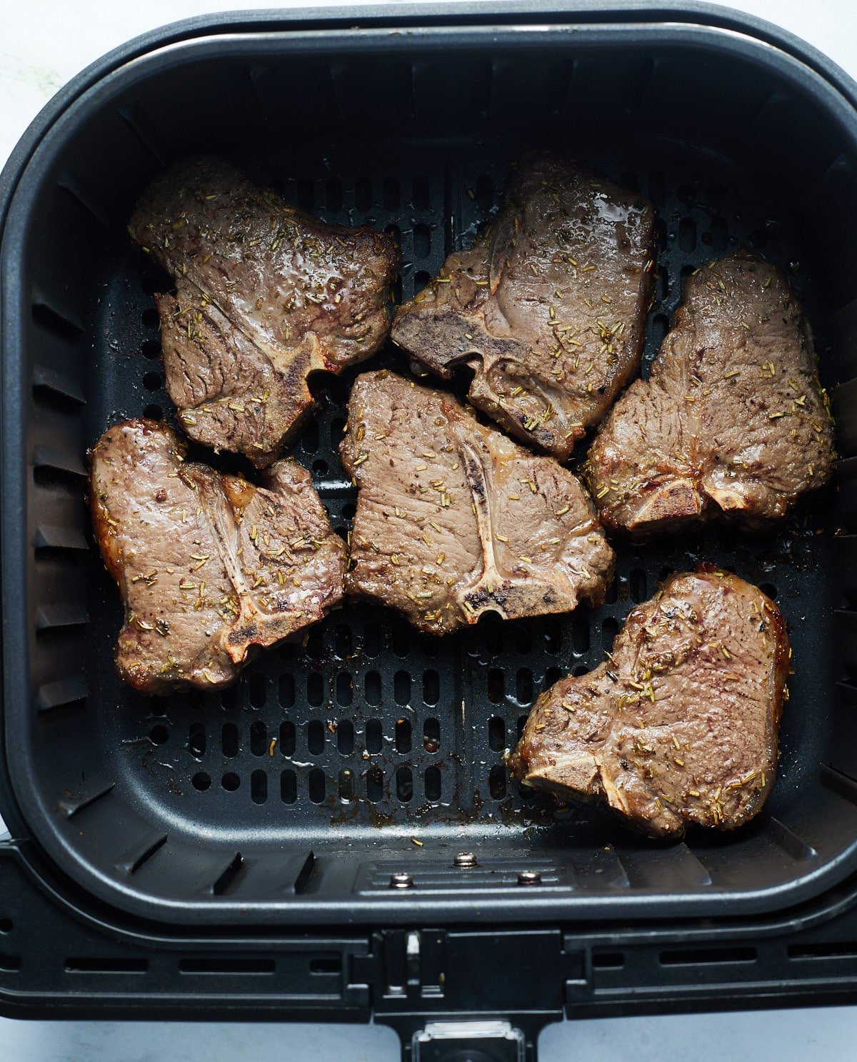 Cooked lamb chops in the air fryer basket.