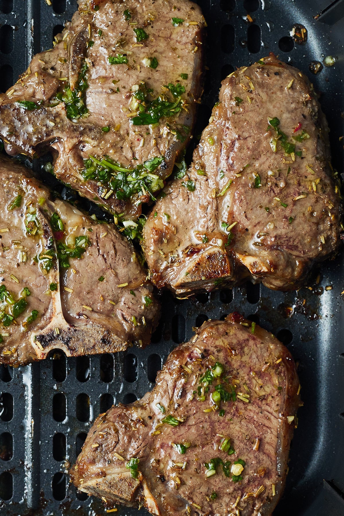 Close up of the cooked lamb chops in the air fryer with chimicurri sauce on it.