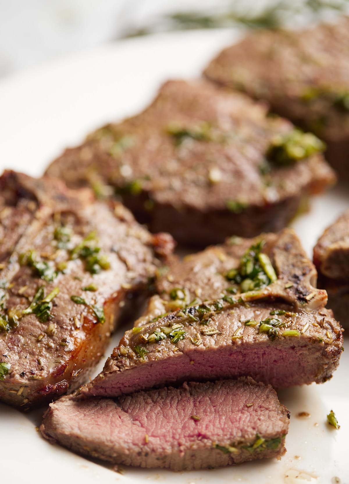 Lamb chops on a white plate with the end cut off.