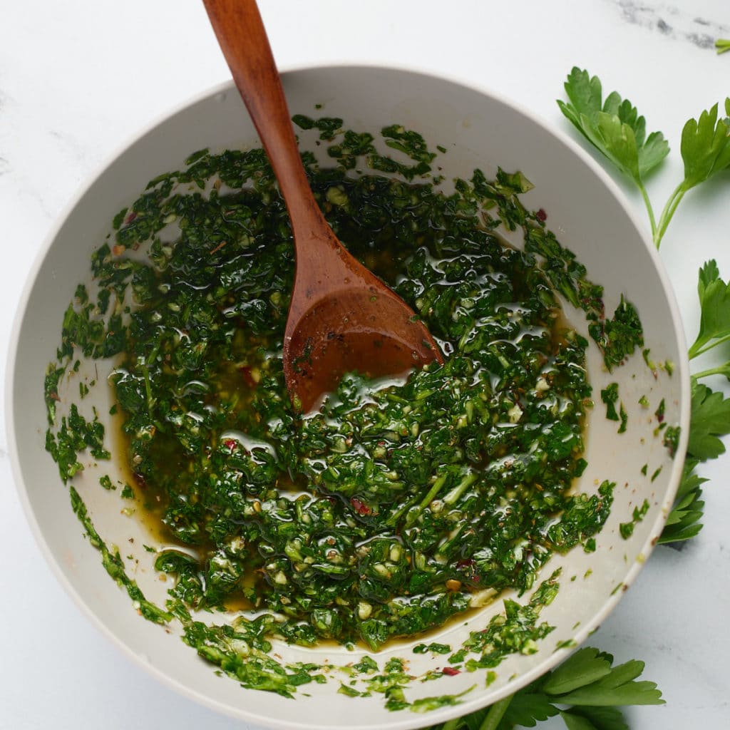 Green chimichurri in a white bowl ready to serve.