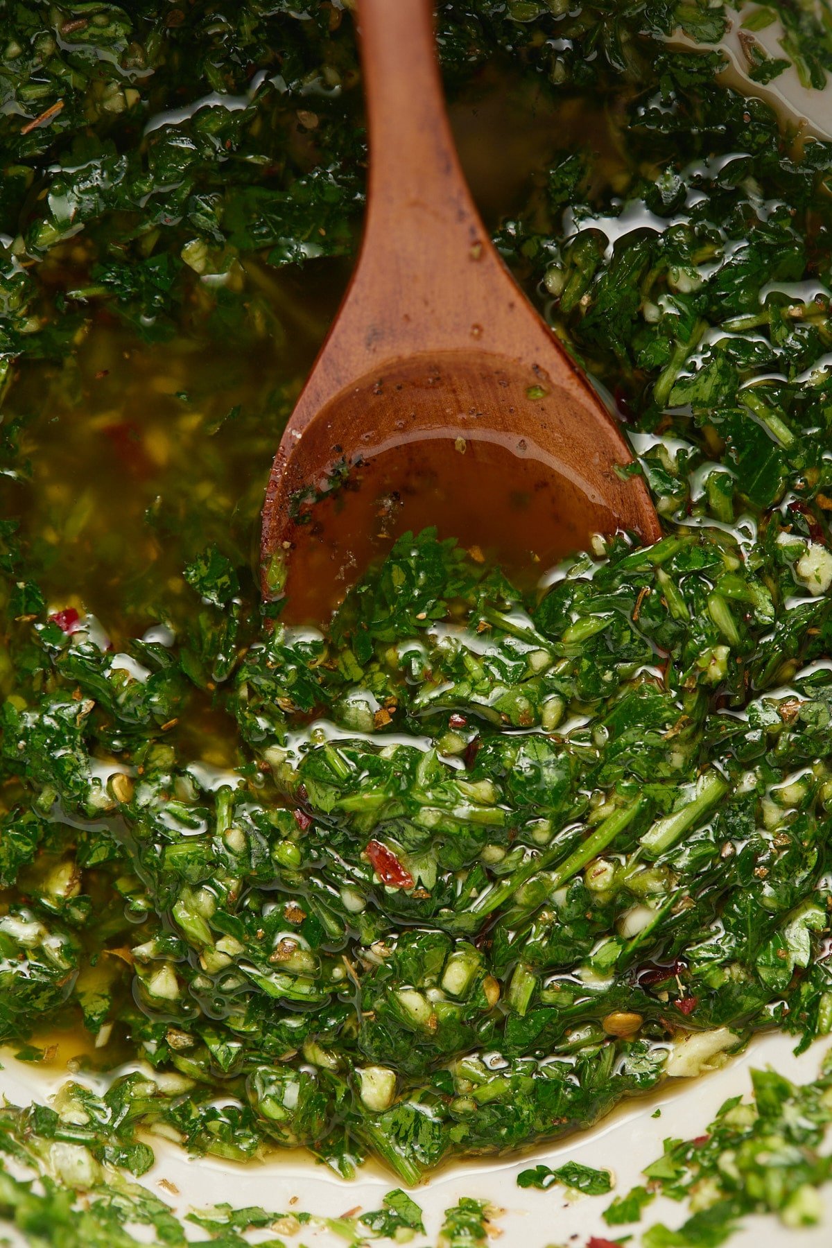 Close up of a wooden spoon in the green herb sauce.