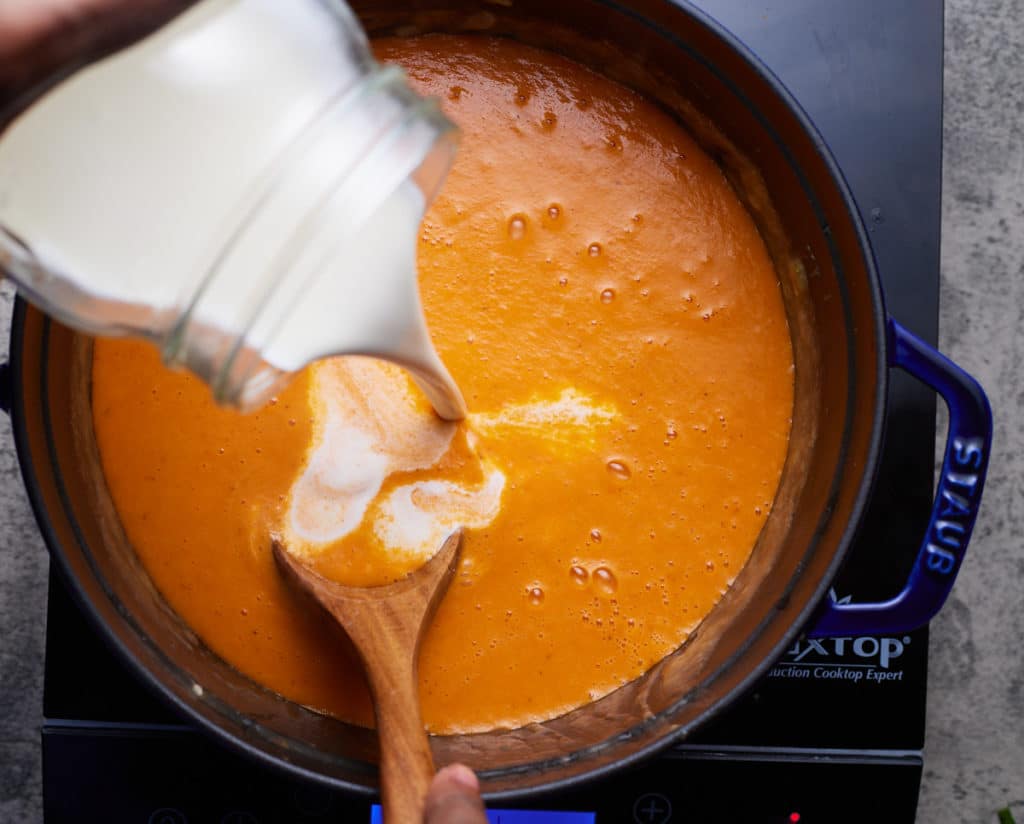 heavy cream being poured in crab bisque