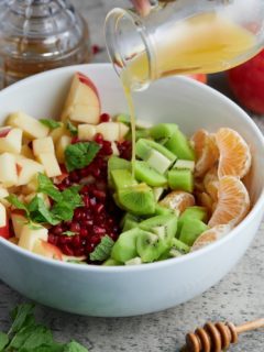 orange juice being poured over fruit salad