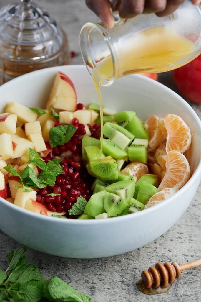 orange juice being poured over fruit salad