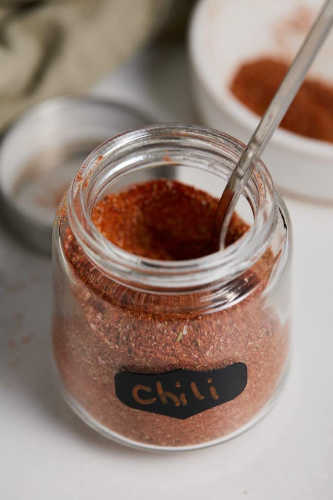 Chili powder in a labelled jar with a spoon.
