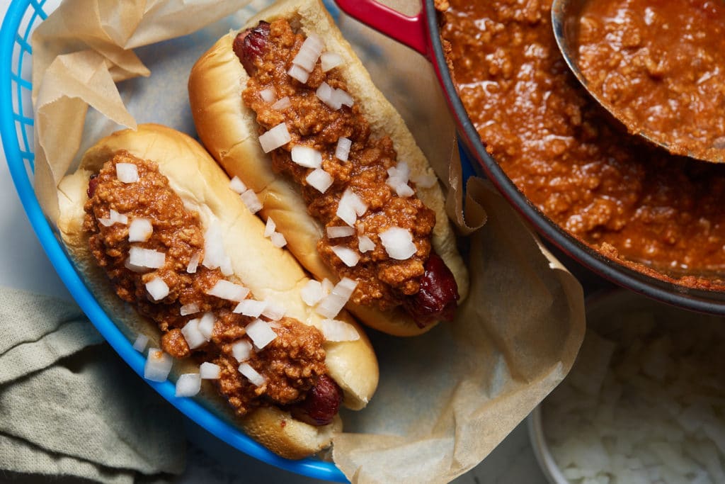 Two chili hot dogs served on a plate ready to eat.