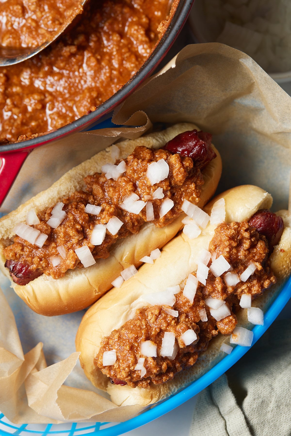 Hot dogs topped with chili on a blue plate.