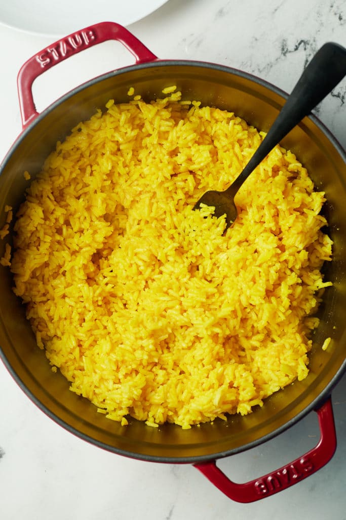 A fork in the pot of rice fluffing the grains.