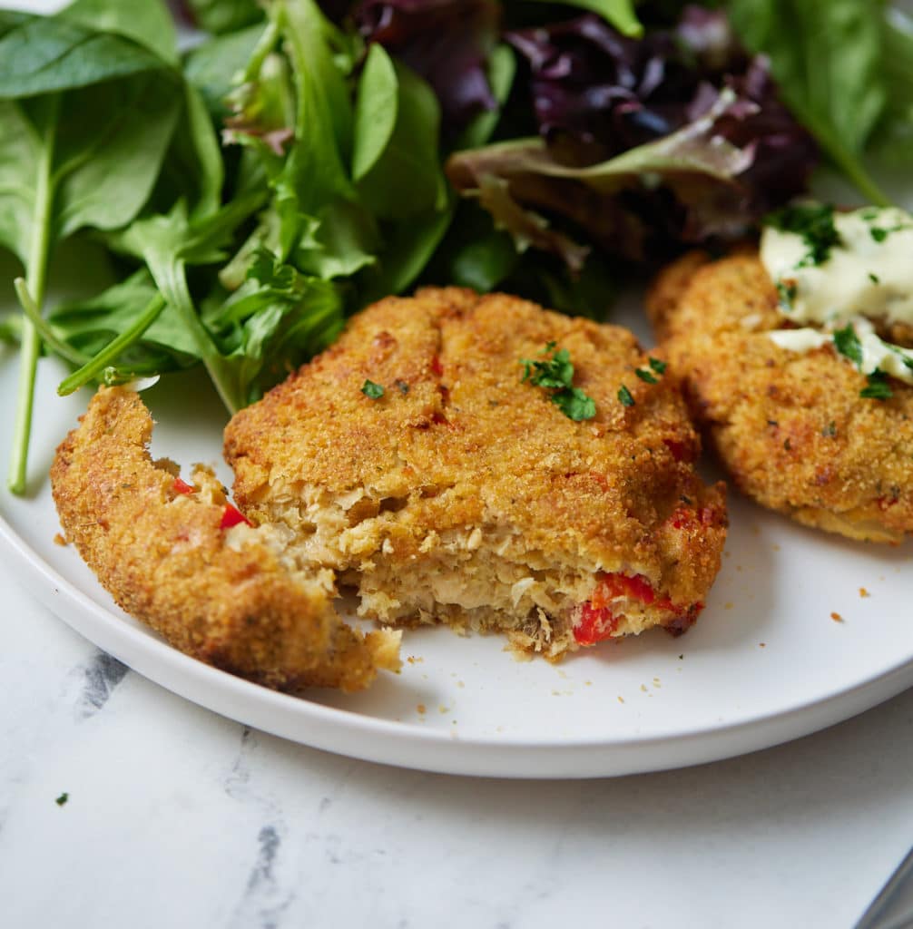 Salmon patty on white plate cut in half to show inside