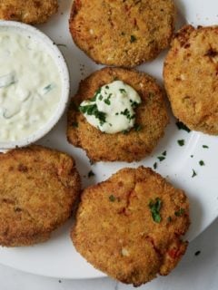 air fryer salmon patties on white plate with tartar sauce on one