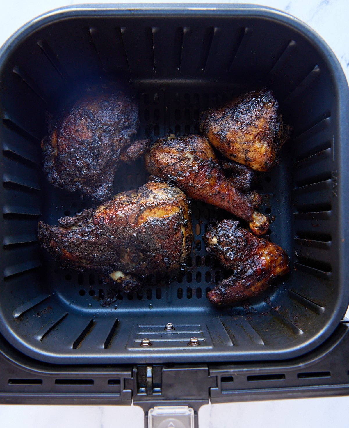 The cooked Jamaican jerk chicken in the air fryer basket.