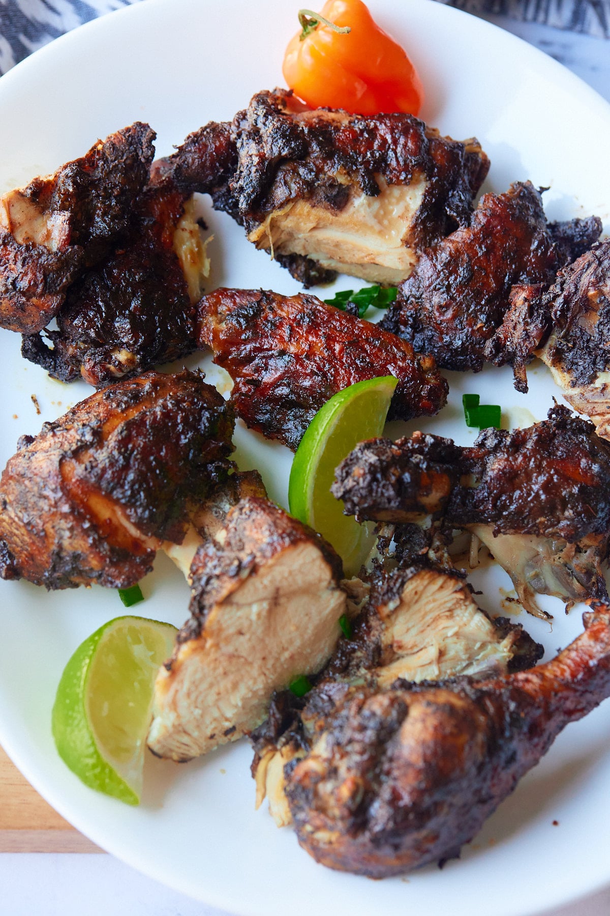 Chopped Jamaican jerk chicken served on a plate with lime wedges.
