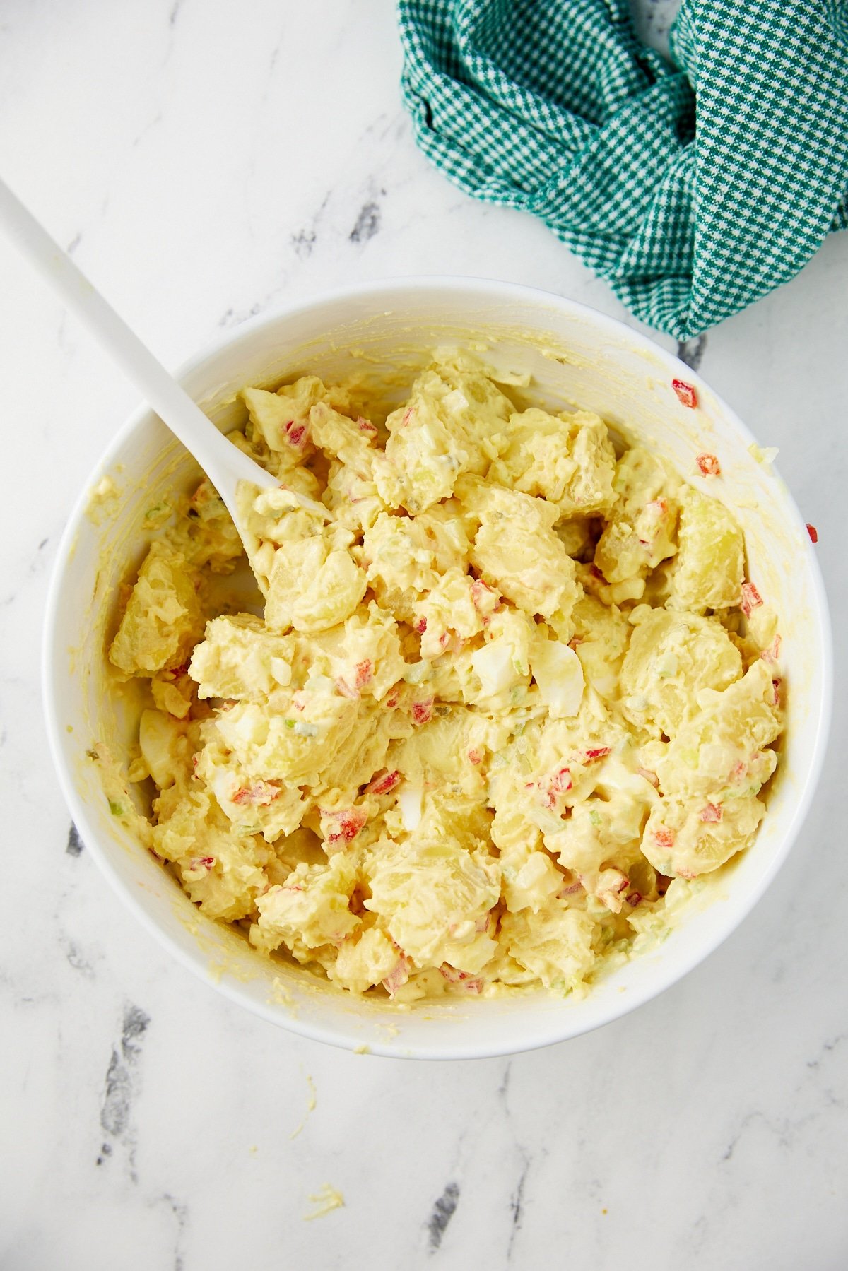 The potato salad mixed together in a white bowl.