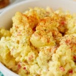 Southern potato salad dressing in a white bowl sprinkled with paprika.