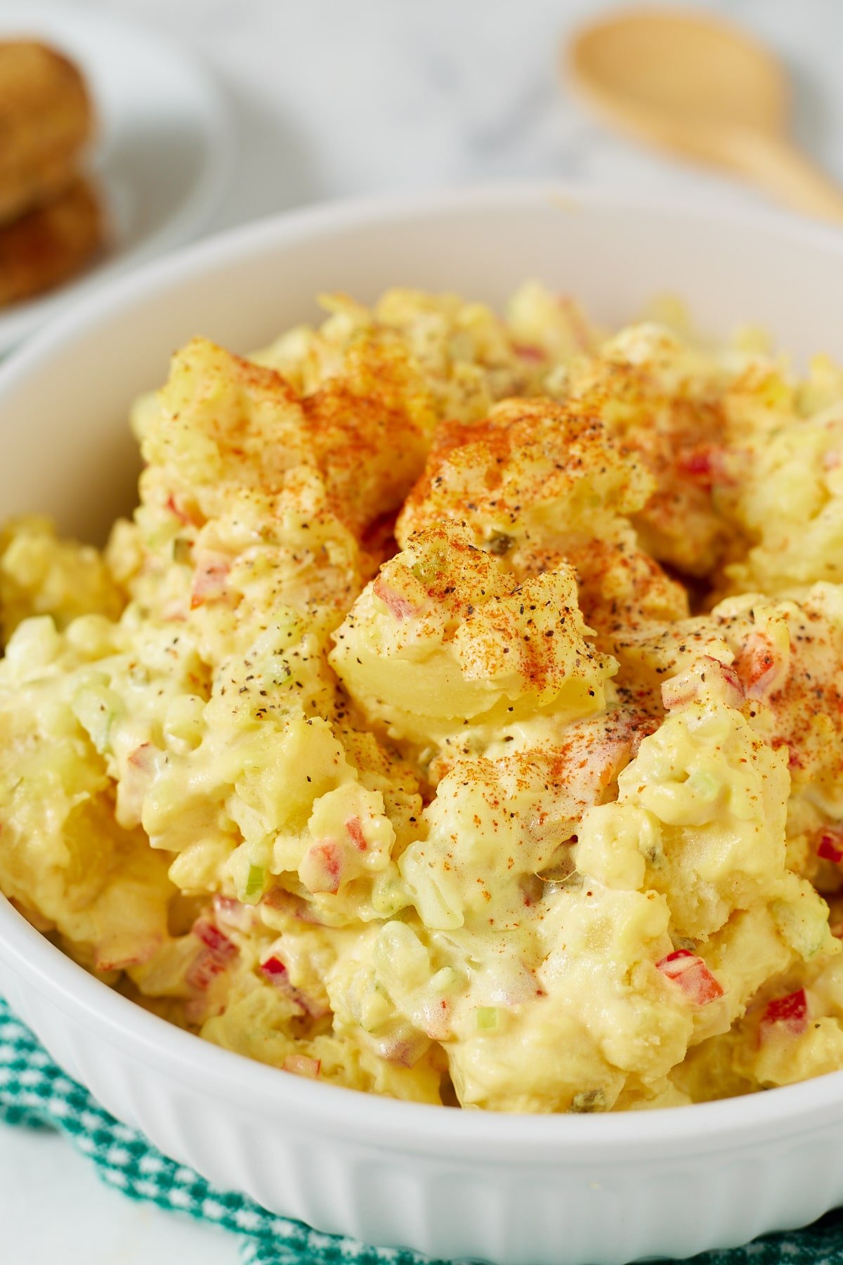 Southern potato salad dressing in a white bowl sprinkled with paprika.