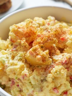 southern potato salad in bowl topped with paprika