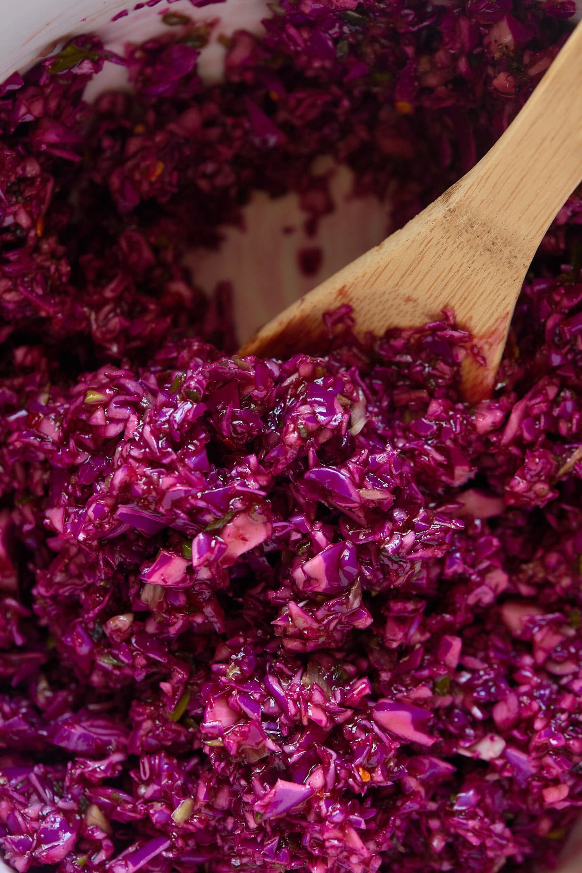 Close up of a wooden spoon in the vinegar coleslaw.