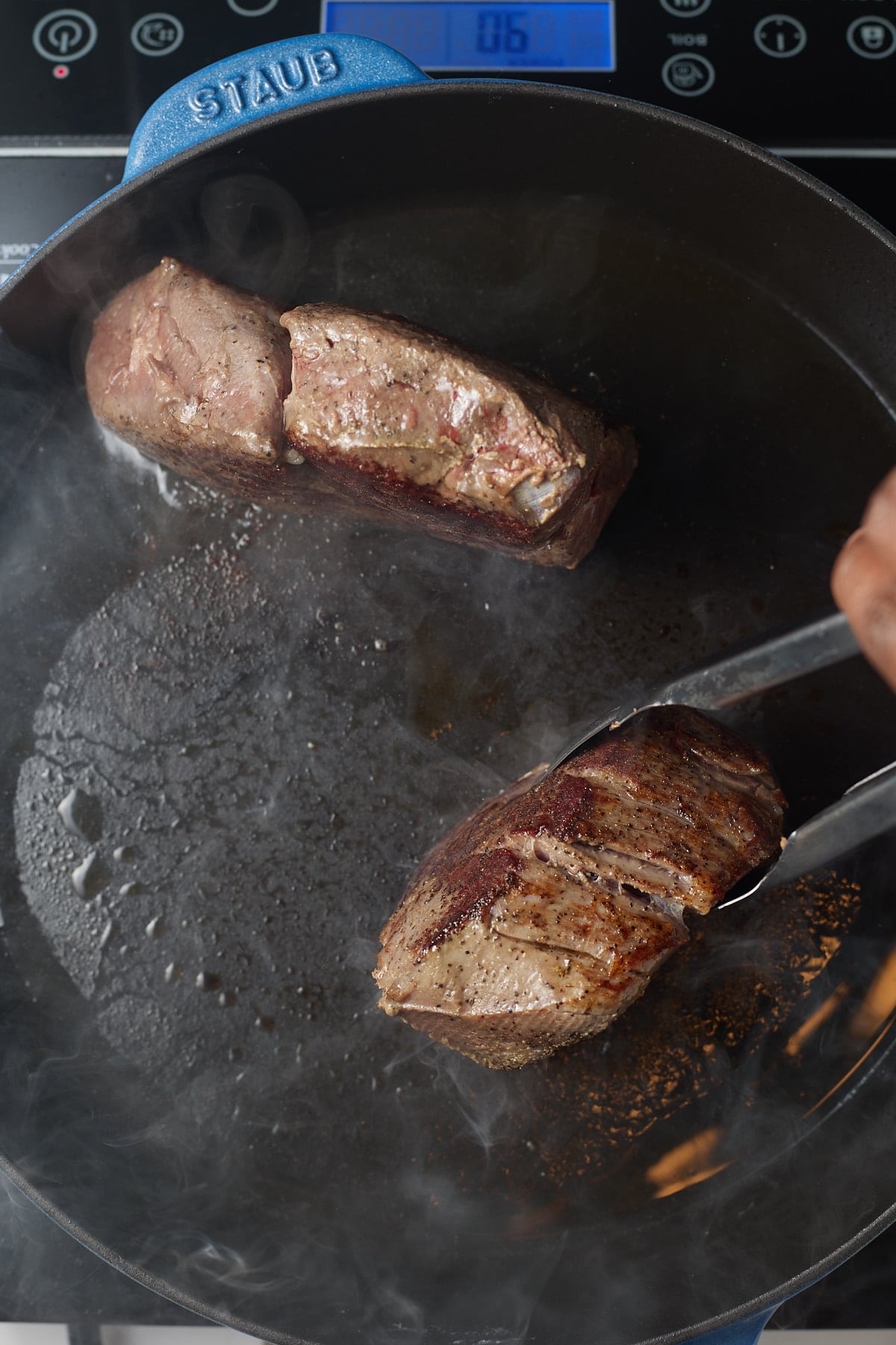 Searing the steaks in a hot pan.