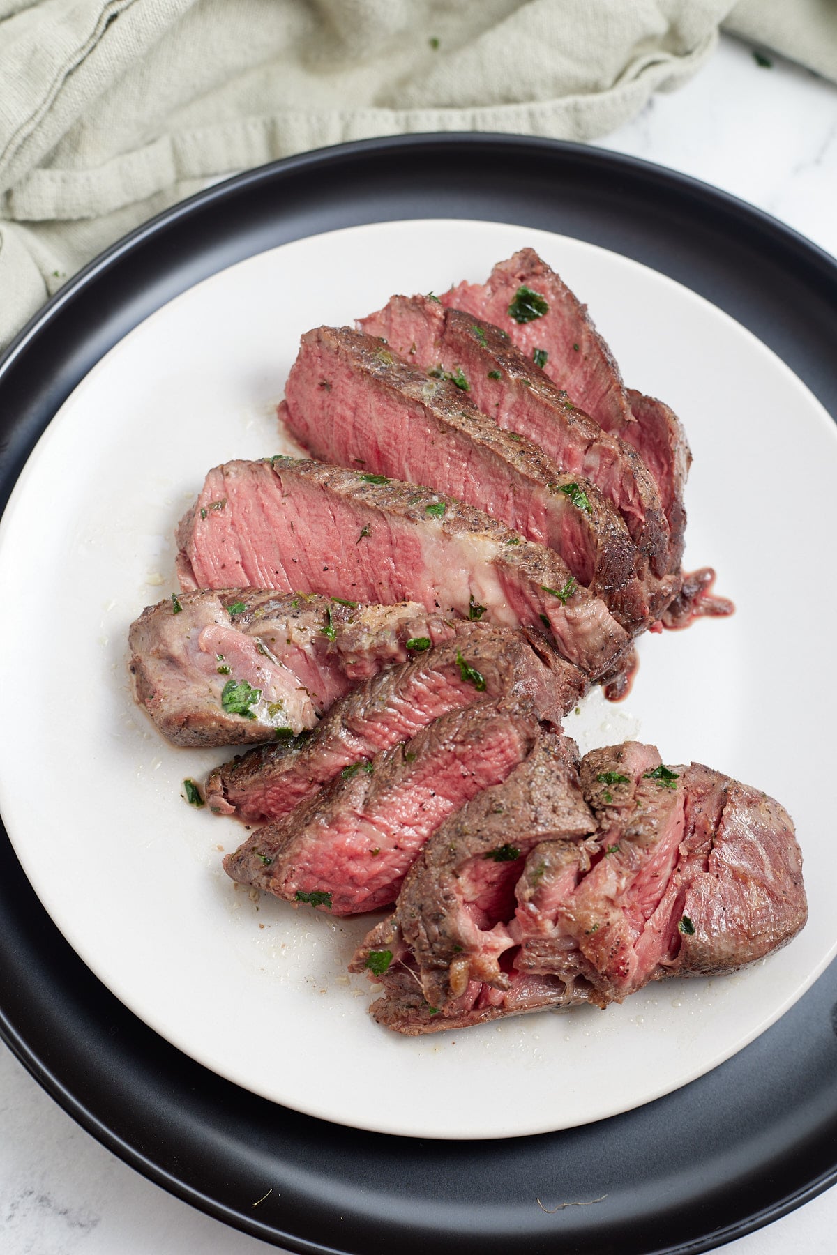 Sliced sous vide filet mignon on a white plate.