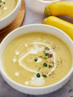 Yellow squash soup served in two white bowls.