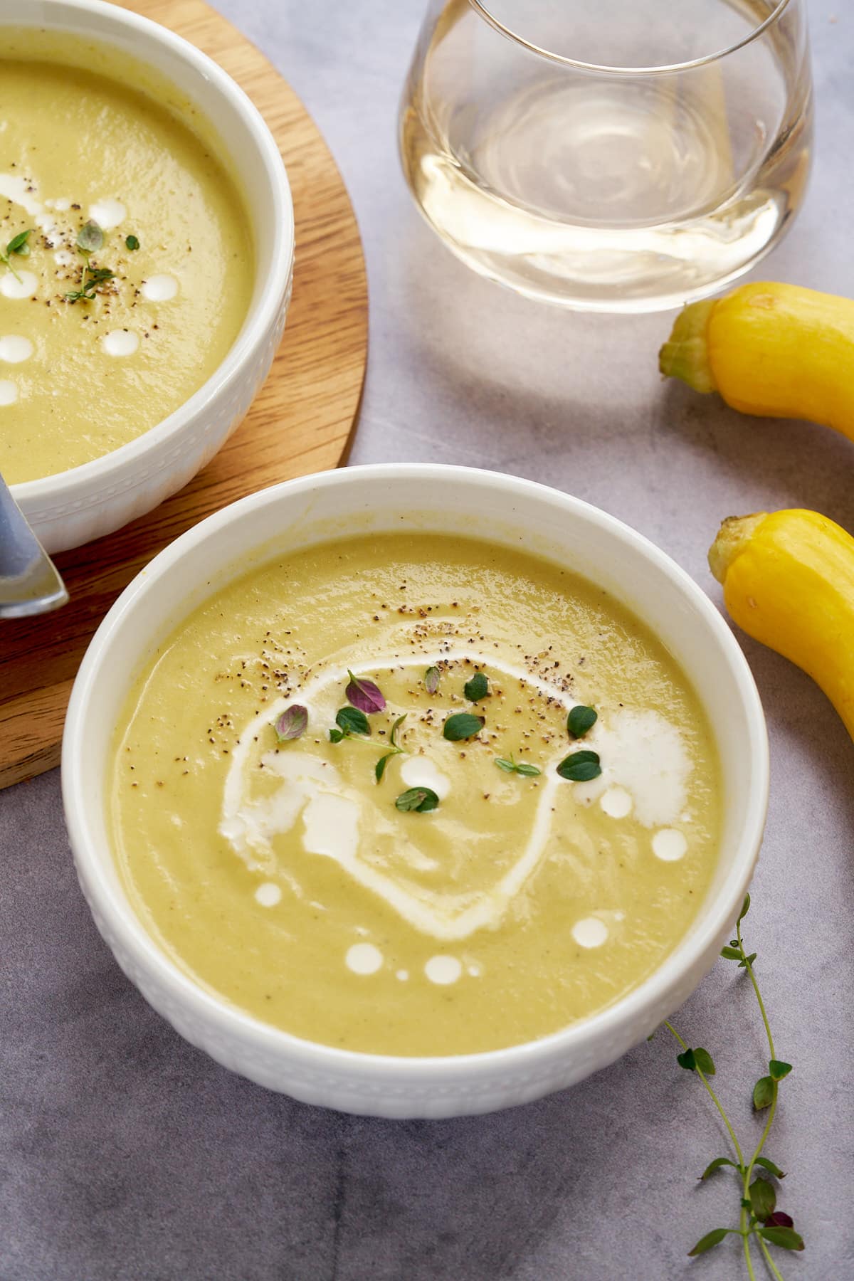 yellow squash soup in white bowl with thyme leaves on top