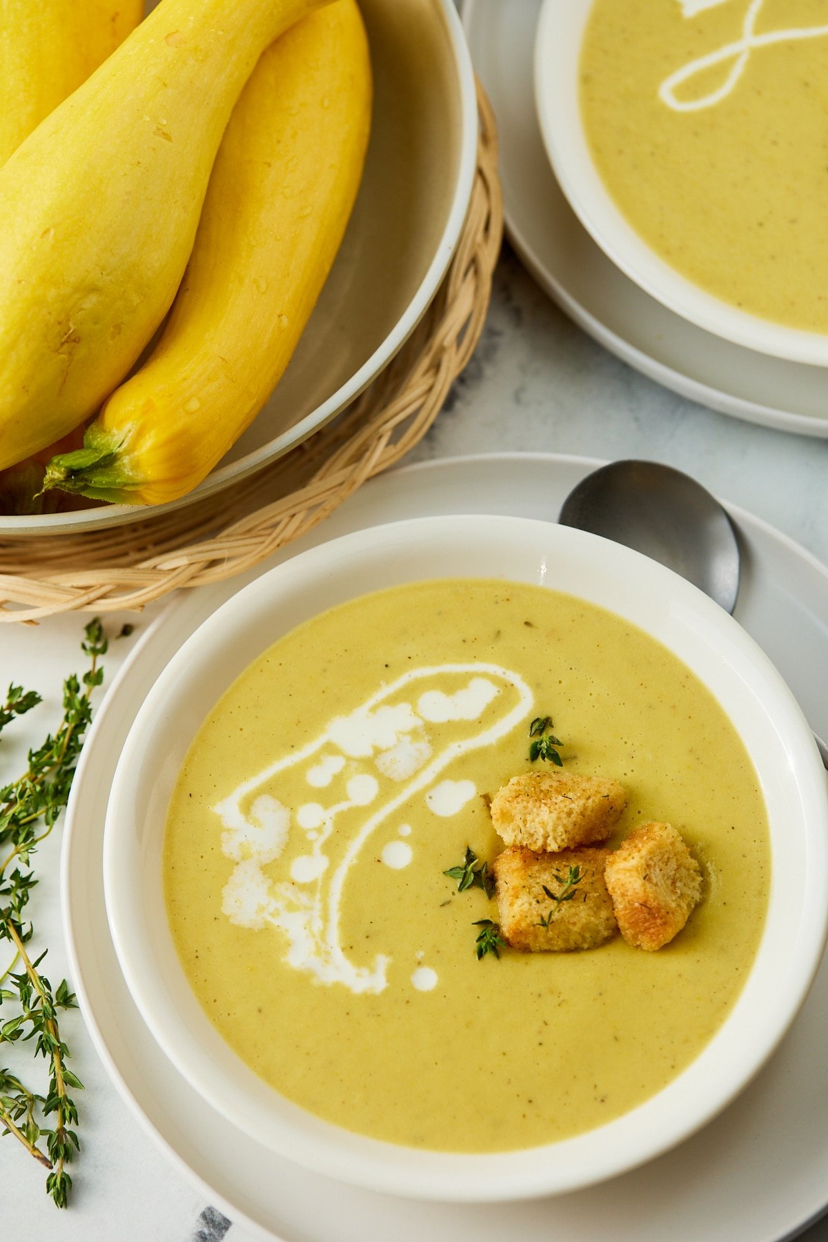 Yellow squash soup served in a white bowl with croutons.
