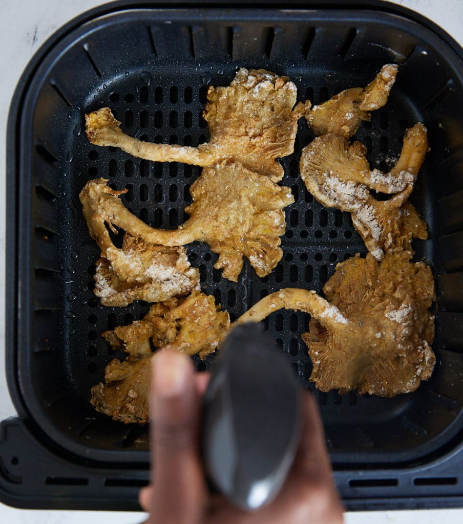 Flipping the mushrooms halfway through cooking.