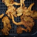 Fried mushrooms in an air fryer basket.