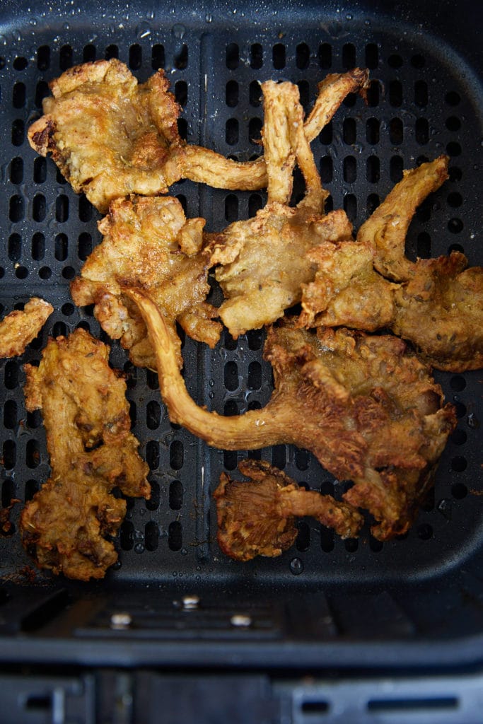 Fried mushrooms in an air fryer basket.