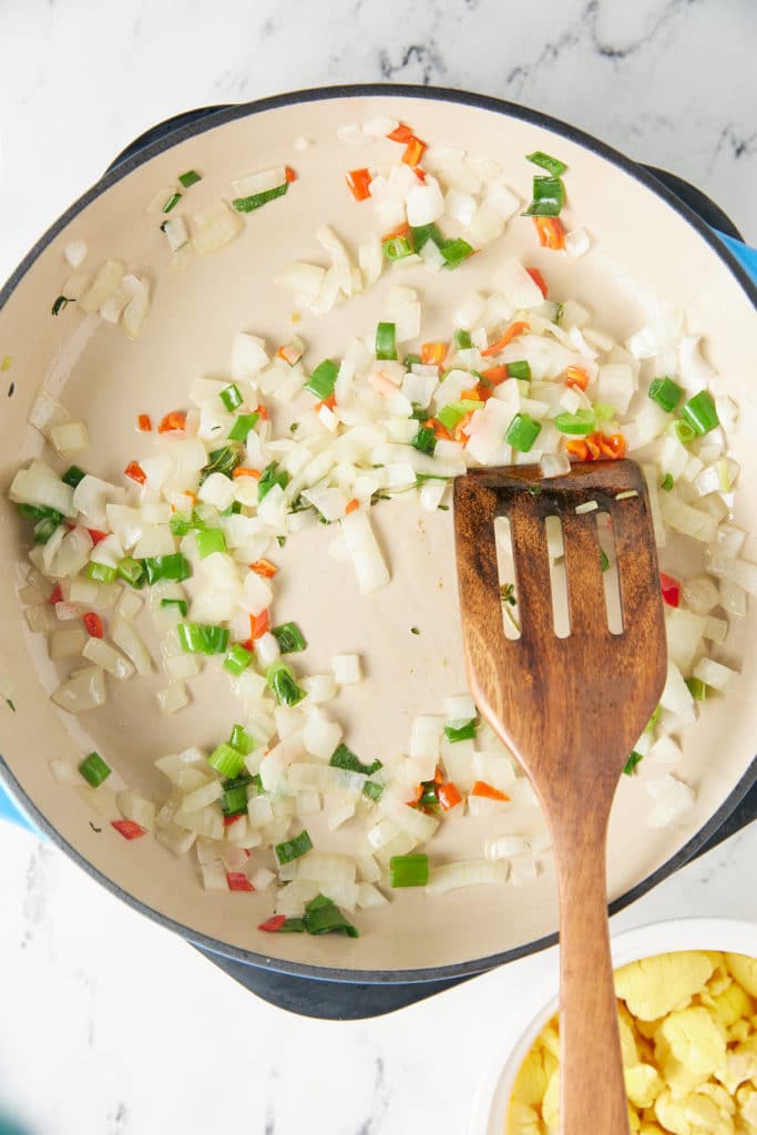 onions, peppers in skillet with wooden spatula sticking out