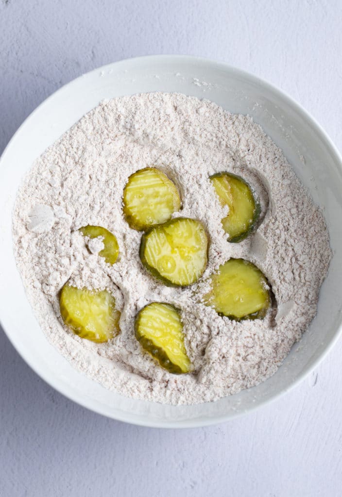 Sliced pickles being coated in flour.