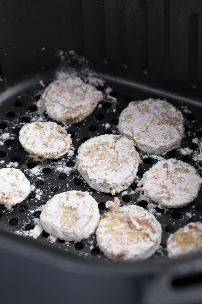 The dredged pickles in the air fryer basket.