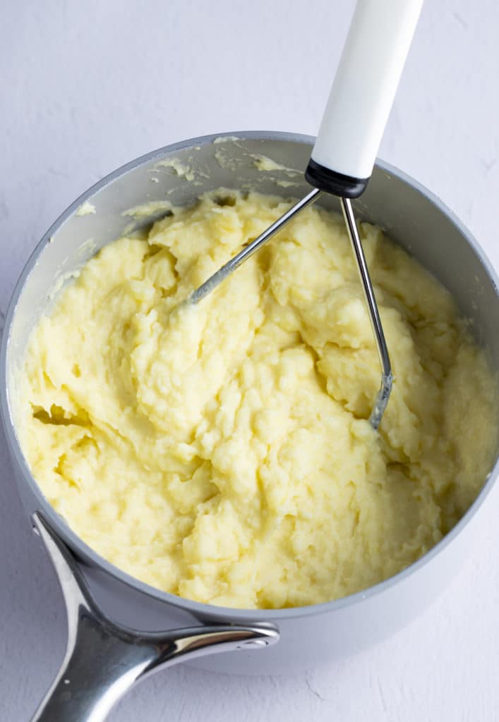 Mashing the potatoes in a pot.