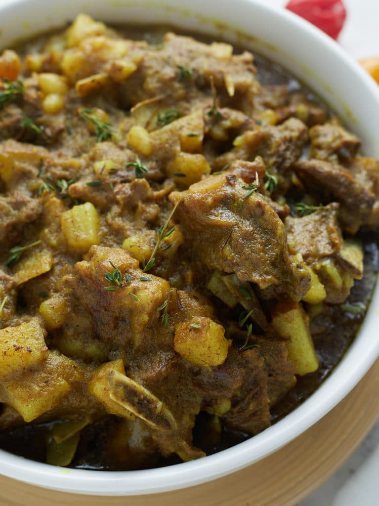 close up photo of curry goat in white bowl