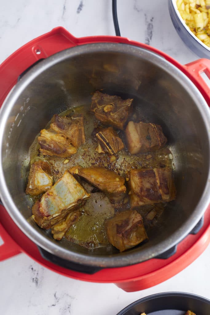 goat being seared in an instant pot pressure cooker