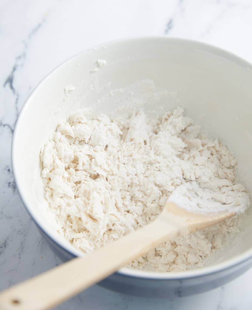 flour, baking soda, and milk stirred in a bowl with wooden spoon sticking out