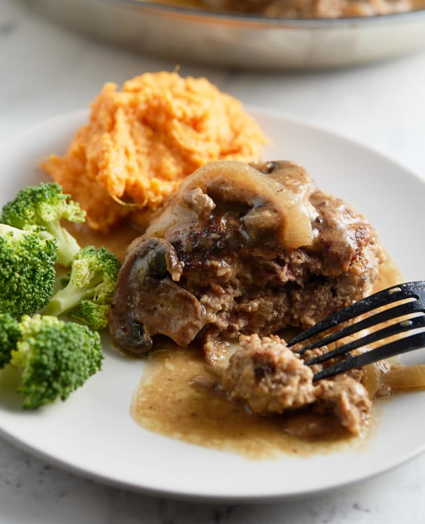 A salisbury steak topped with mushroom gravy on a white plate.