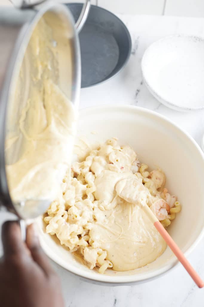 The sauce being poured over the macaroni.