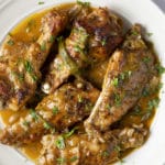 Five smothered turkey wings on a white plate.