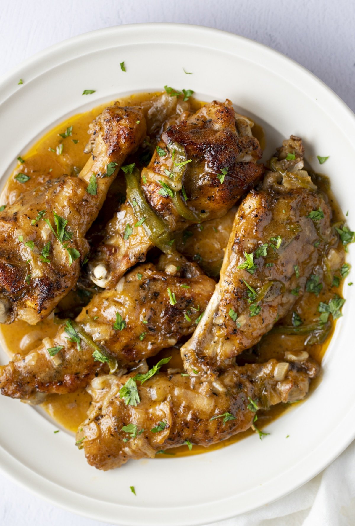 Five smothered turkey wings on a white plate.