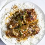Smothered turkey wings and rice served on a white plate.